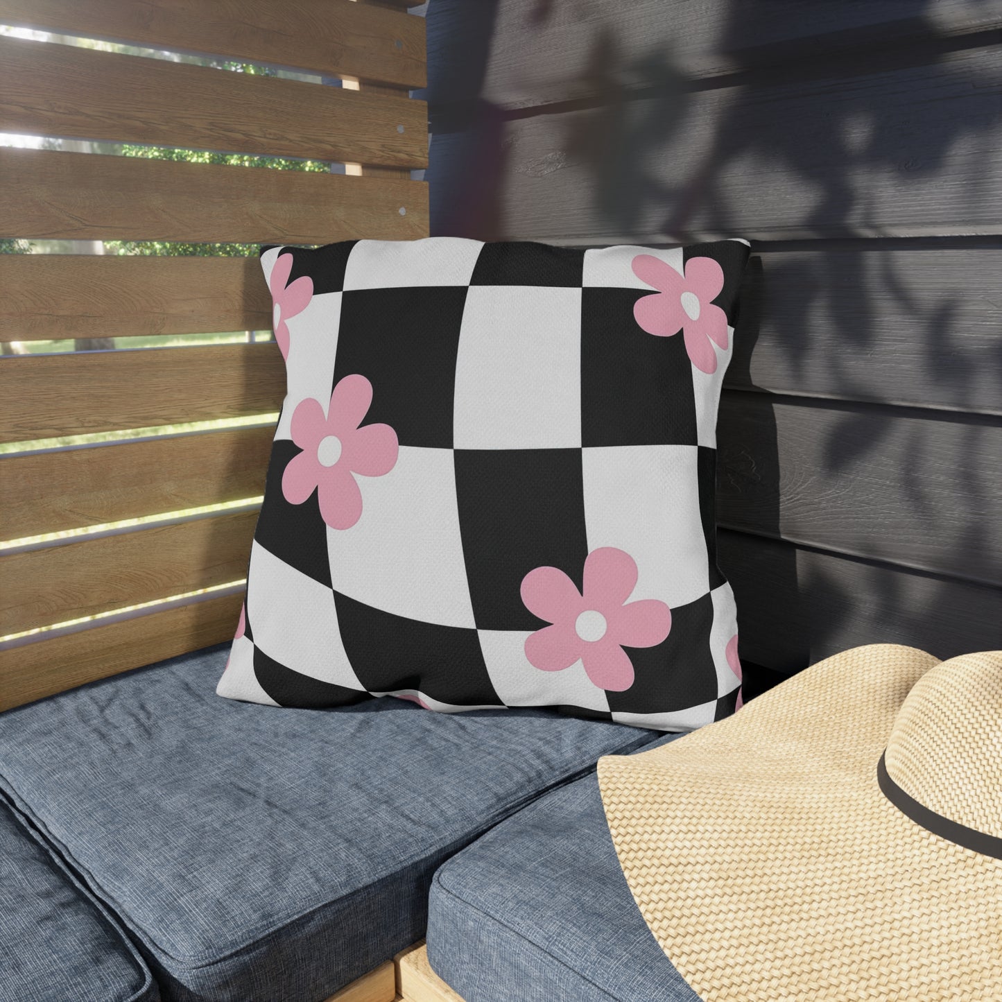 Square floral cushion with pink blossoms over a modern grid design for garden seating