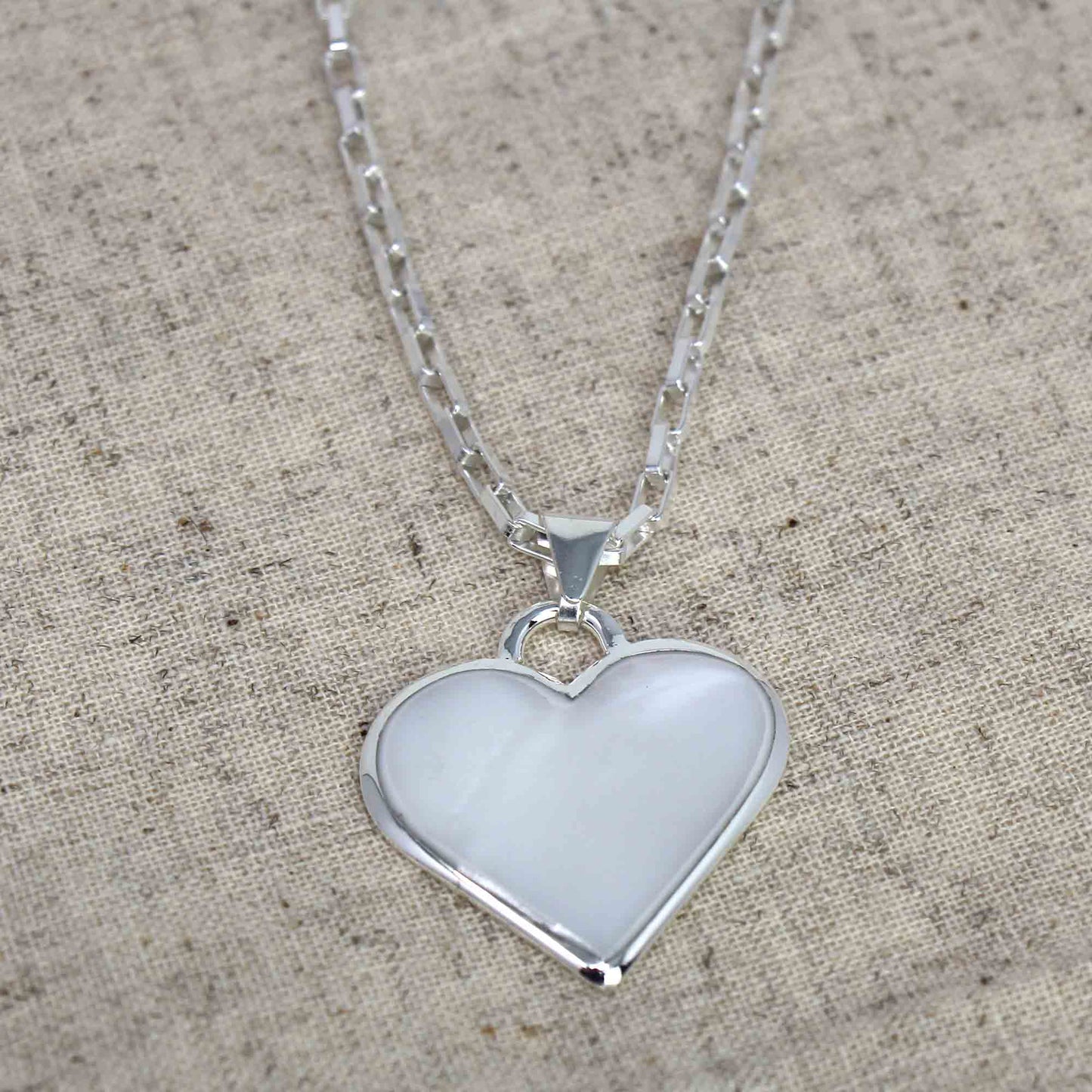 Close-up of white heart-shaped necklace with shimmering shell detail
