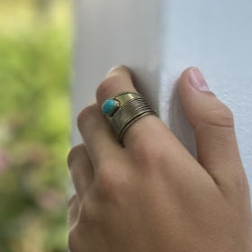 Adjustable brass ring with bold turquoise stone, artisan-crafted with a bohemian aesthetic.