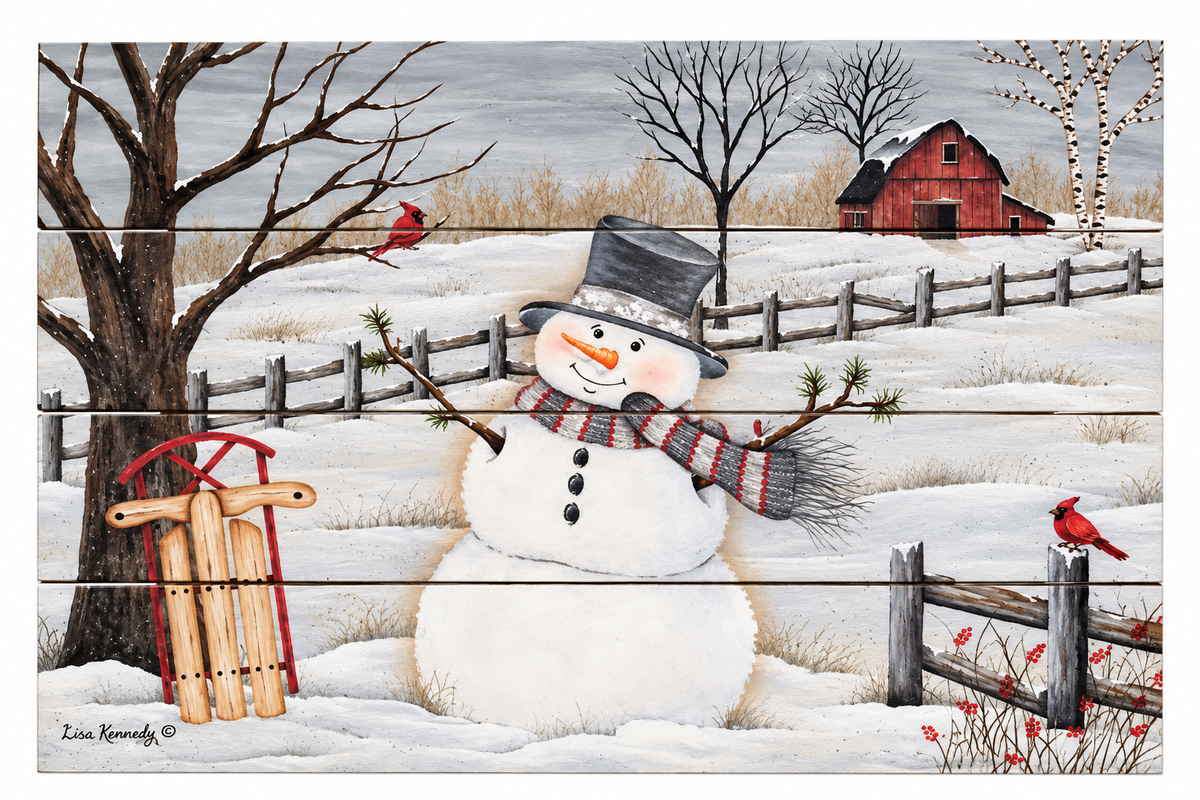 A winter landscape art print featuring a snowman in a snowy field with a red barn, bare trees, a fence, and red cardinals. The print has a horizontal wood-plank texture and is signed by artist Lisa Kennedy in the lower left corner.