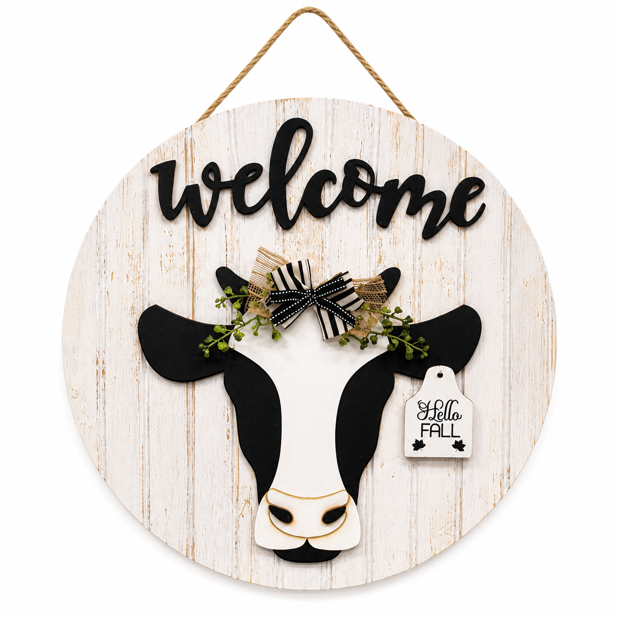 Round wooden welcome sign with black and white cow, raised welcome lettering, jute hanger, and interchangeable seasonal ear tag for farmhouse wall or door décor