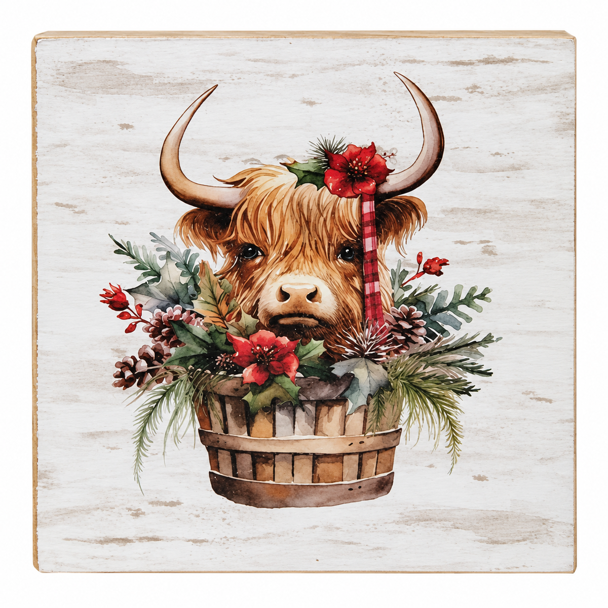 A square decorative wall plaque featuring a painted Highland cow head with curved horns, surrounded by a rustic wooden basket filled with red flowers, green foliage, pinecones, and a red-and-white striped candy cane, set against a distressed off-white wood background.