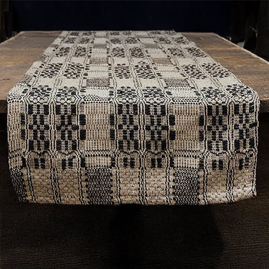 Black and tan checkered woven table runner folded on white surface
