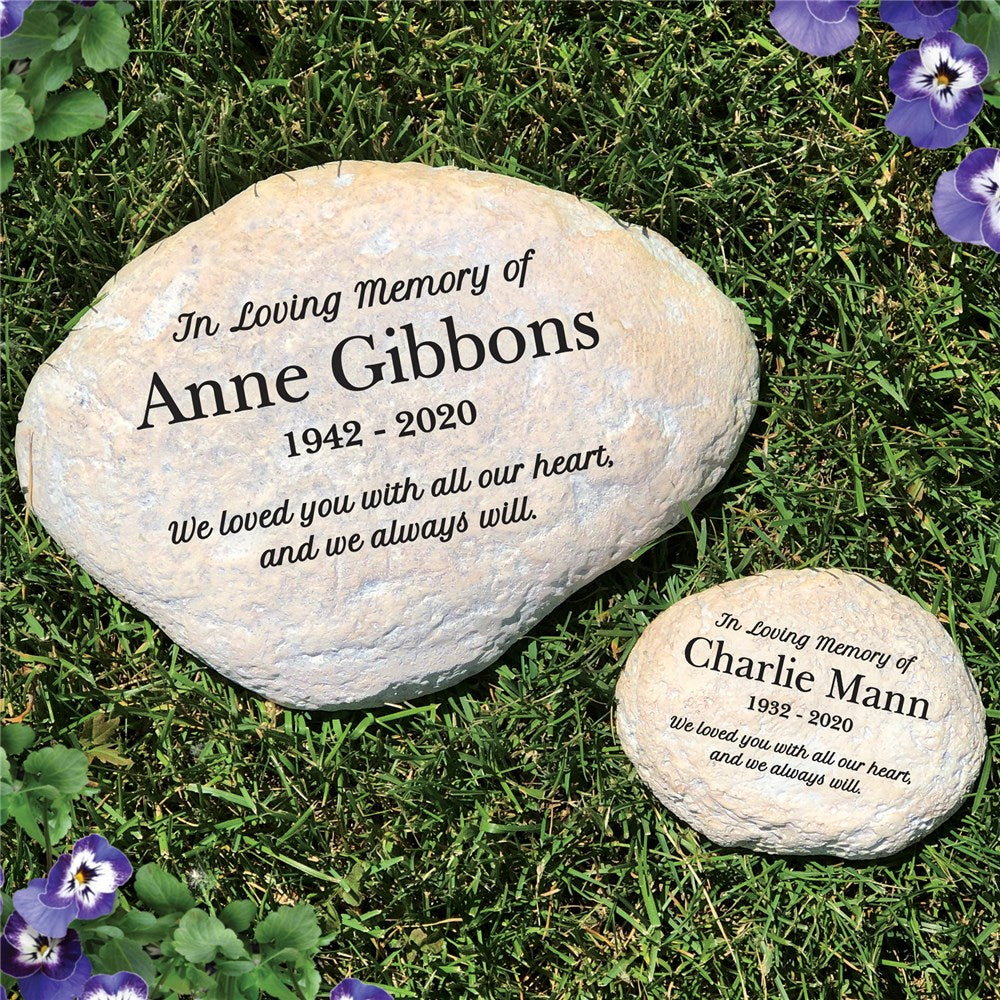 Personalized memorial garden stone engraved with name and dates, shown resting on a patch of grass with natural texture and shape.