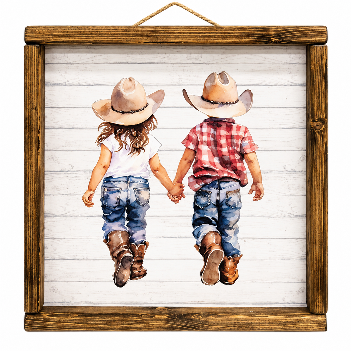 A square framed art print featuring a watercolor-style illustration of two children in cowboy hats and jeans holding hands, viewed from behind, set against a white wood plank background. The artwork is enclosed in a rustic brown wooden frame with a hanging rope at the top.