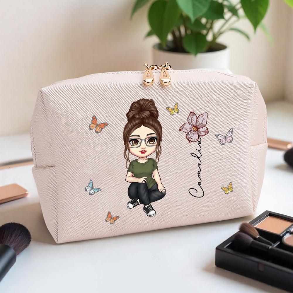 A pink personalized makeup bag sitting on a makeup table, featuring a custom cartoon character, birth flower, and name, showcasing the personalized design in a stylish setting.