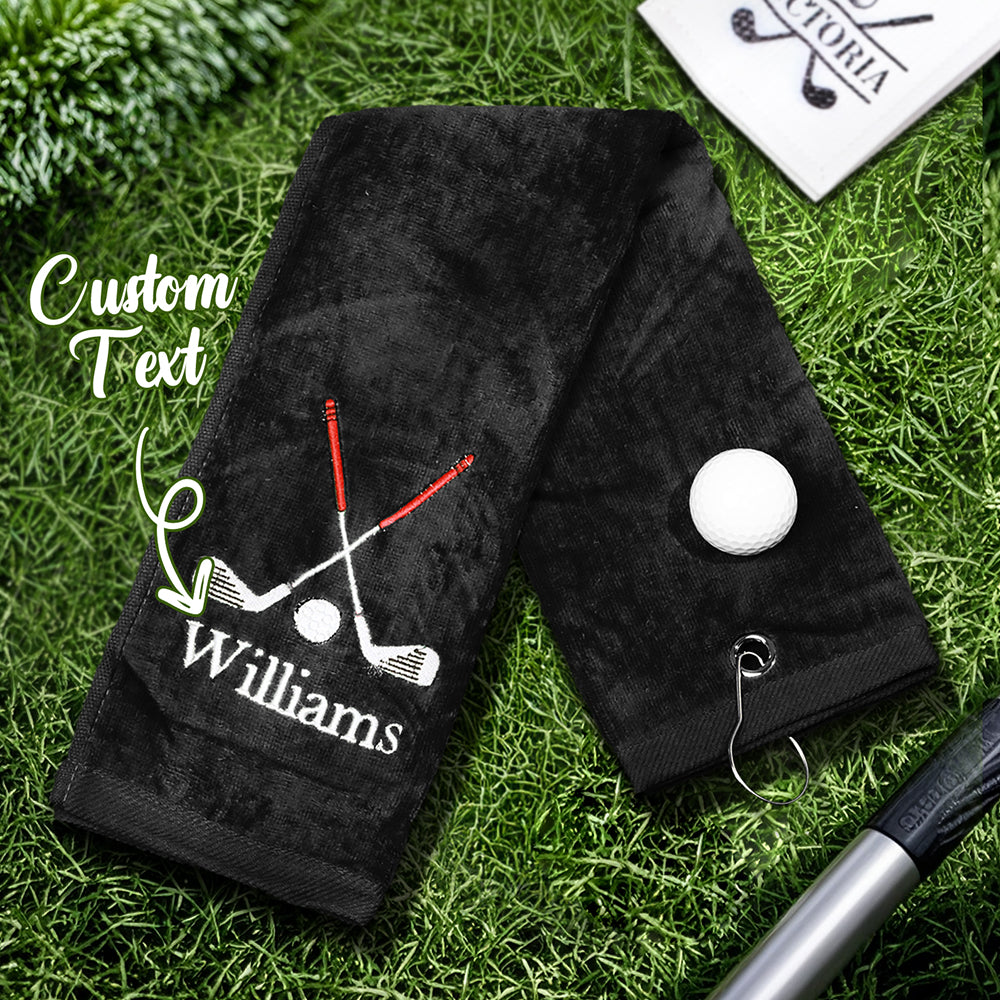 A close-up of the black golf towel with the personalized embroidered last name, showing the soft and absorbent fabric.