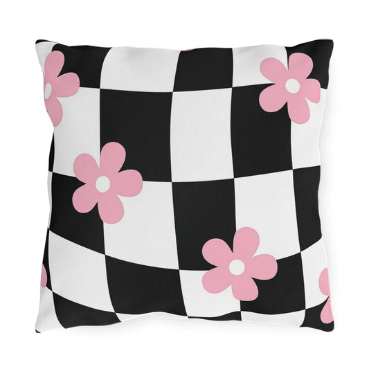 Black and white checkered outdoor pillow with soft pink floral print on a patio bench