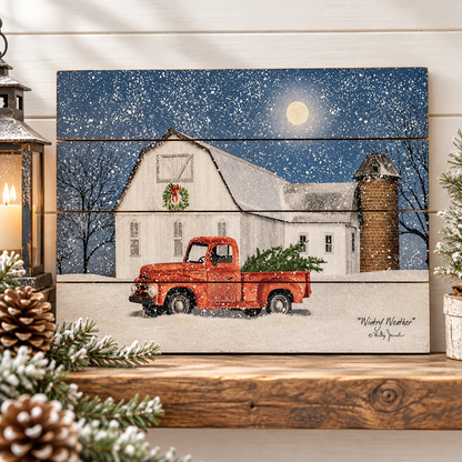 A rustic wooden sign featuring a Christmas night scene with a red pickup truck carrying a green tree in front of a snow-covered white barn, displayed on a wooden shelf with holiday decorations.