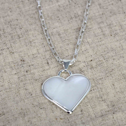 Close-up of white heart-shaped necklace with shimmering shell detail