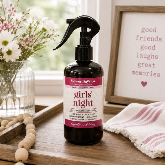 A bottle of Slower Days Co. Girls' Night room spray stands on a wooden tray in a styled home setting.