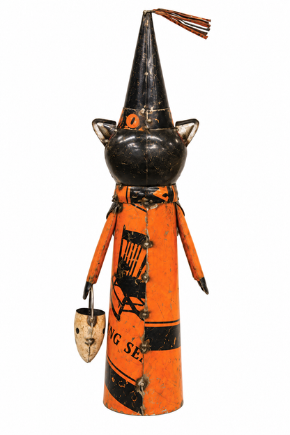 Vintage Halloween witch doll with a black painted head and pointed hat, orange body, black printed graphics, and a small hanging bucket, photographed on a white background.