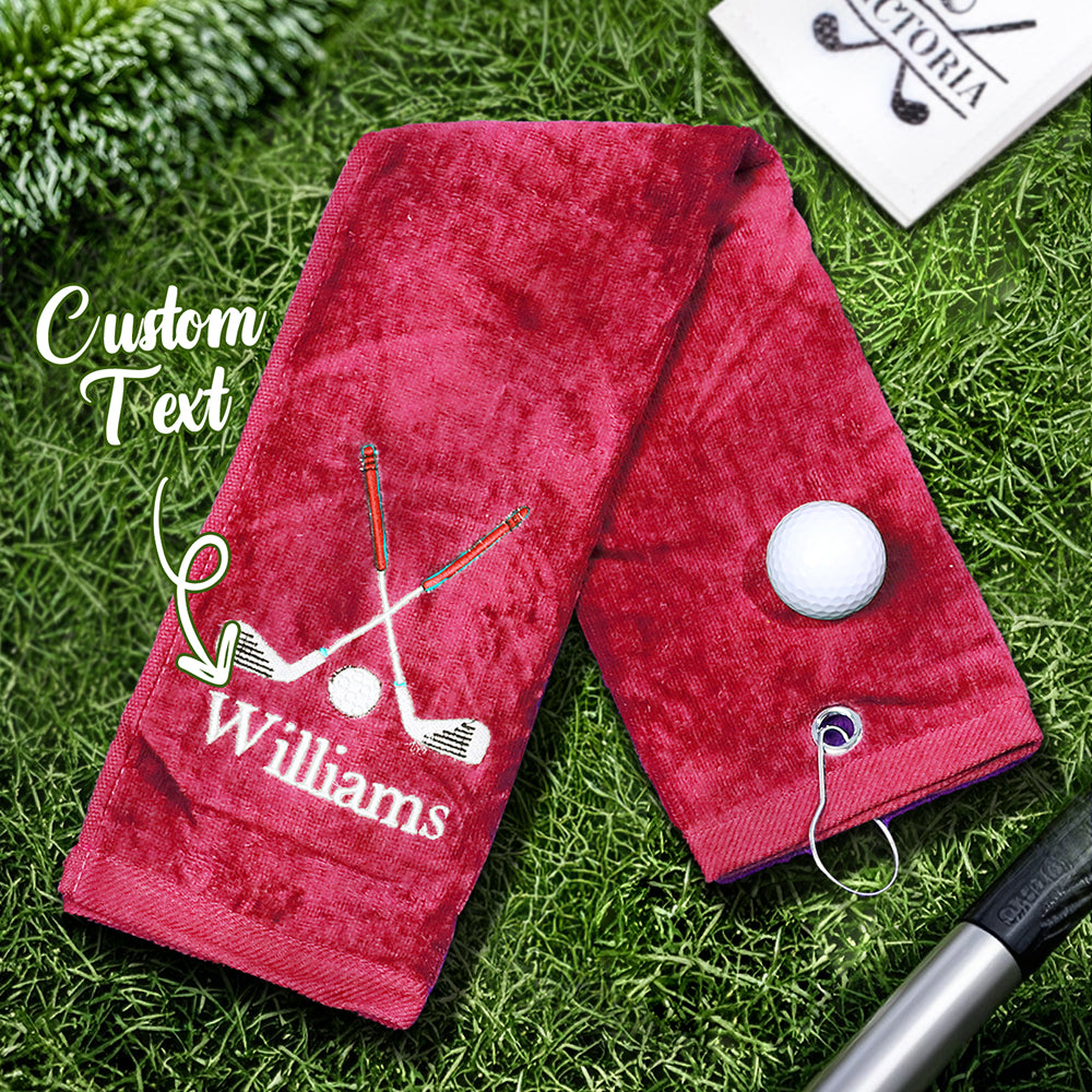 A red golf towel with the customer's personalized embroidered last name, featuring a sturdy clip for easy attachment to golf bags or backpacks.