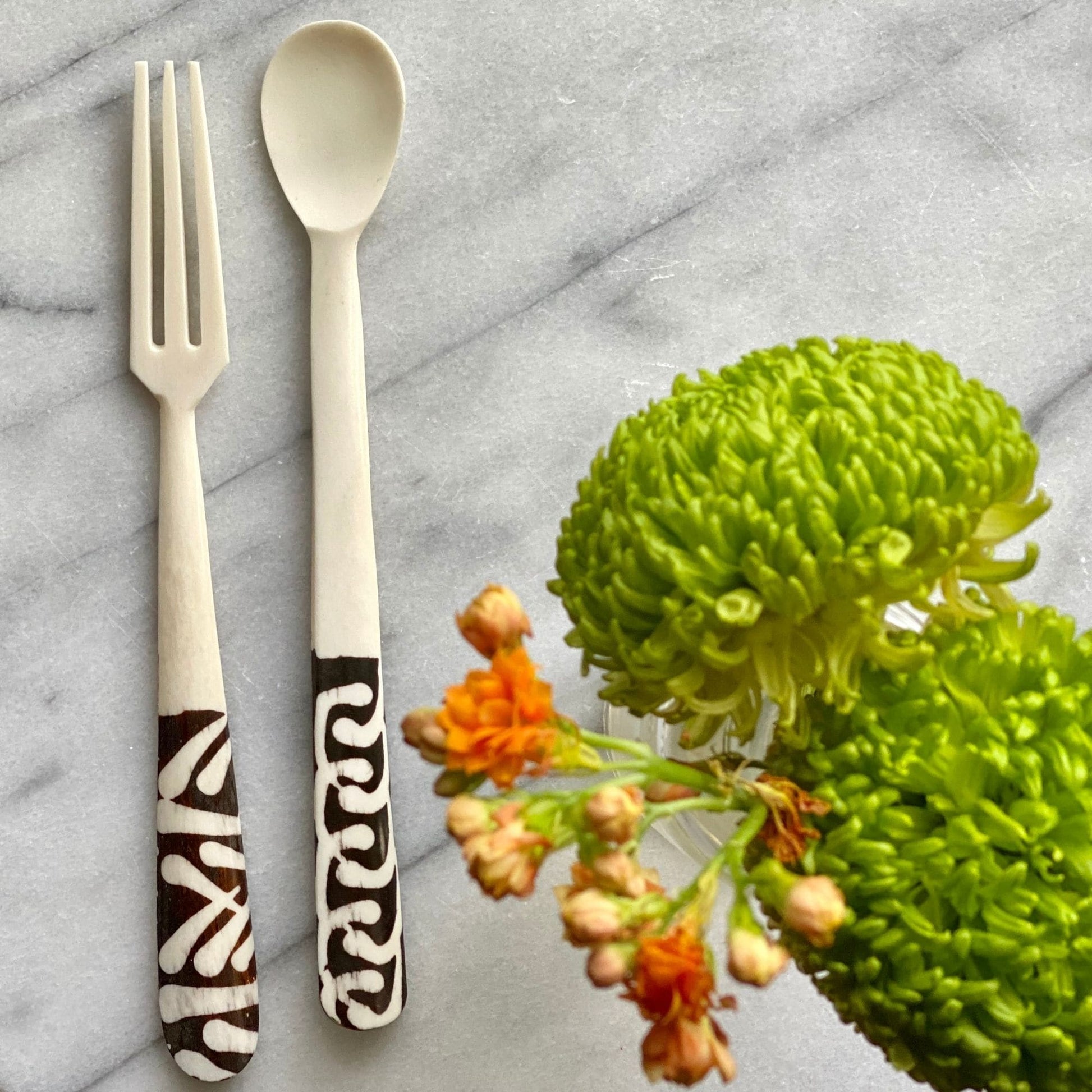 Pair of handcrafted bone appetizer forks resting on a wooden tray