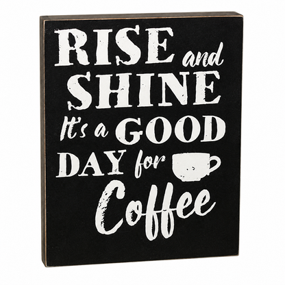 A rectangular black decorative sign with white text reading “RISE and SHINE It’s a GOOD DAY for Coffee,” plus a small coffee cup icon, shown on a plain white background.