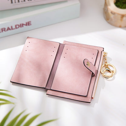 A close-up of the pink vegan leather wallet opened, showcasing the credit card slots, secure snap closure, gold zipper, and keyring for added convenience and style.