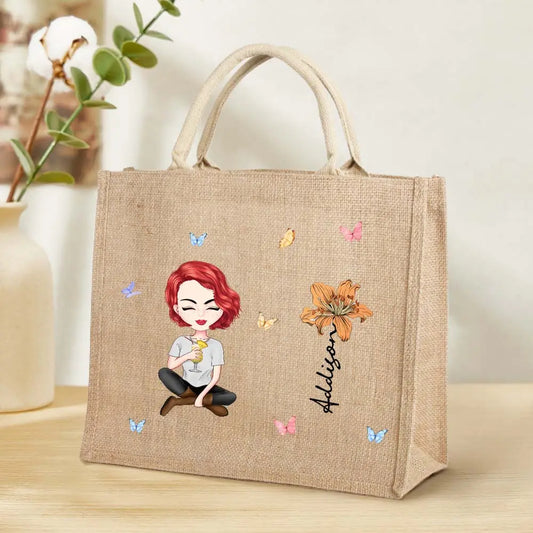 A jute tote bag with a cartoon woman, flower, and custom text, featuring the jute handle.