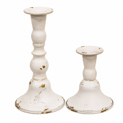 Set of two cream and gold metal taper candle holders with distressed finishes, contoured shapes, and flared bases in coordinating heights.