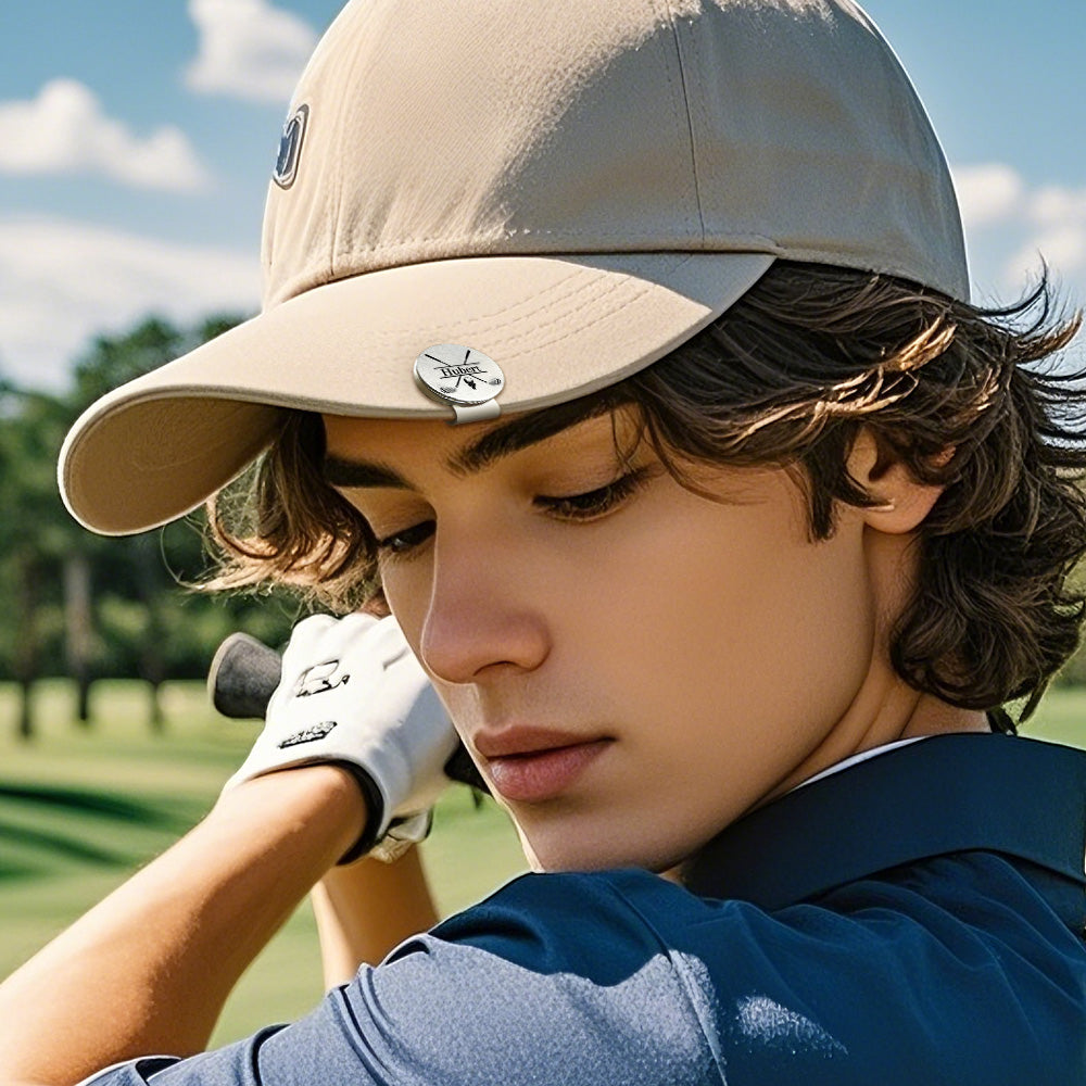 A young man wearing a golf hat with the personalized golf ball marker securely attached to the brim. The sleek magnetic clip keeps the marker easily accessible, allowing for quick use on the course.