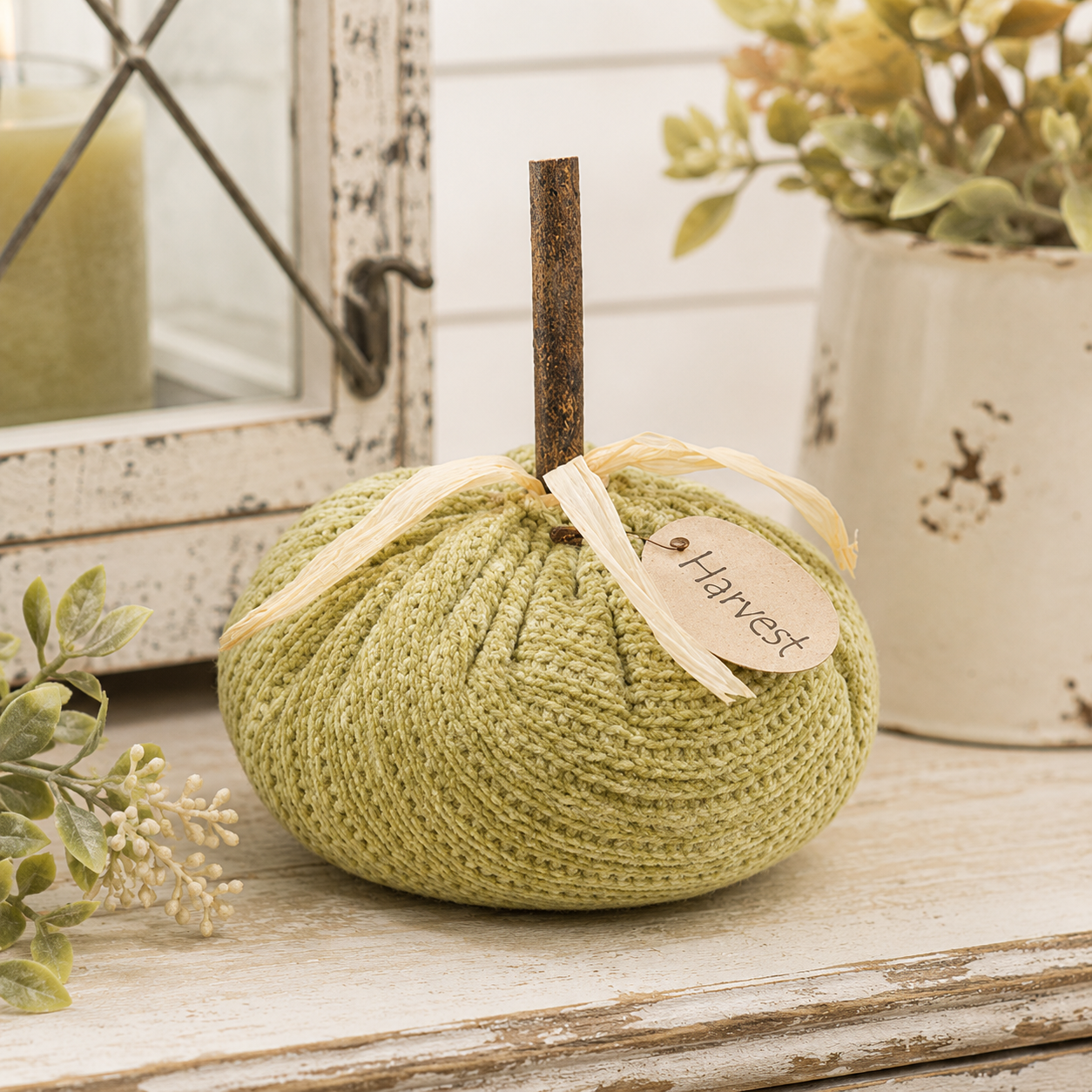 Light green stuffed harvest pumpkin with soft sweater-knit texture, wooden stem, dried grass accents, and a brown Harvest paper tag.