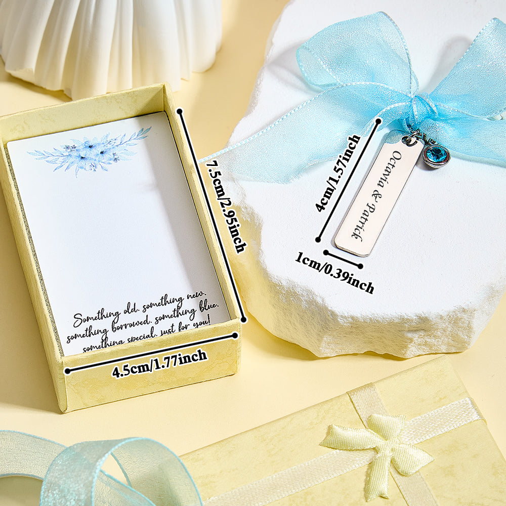 A close-up of the "something blue" charm with a blue ribbon, displaying an overlay with the size of the charm (1.57 inch x 0.39 inch) and the box (2.95 inch x 1.77 inch).