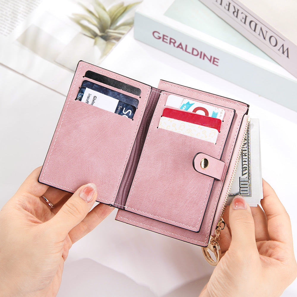 A shot of the pink vegan leather wallet in use, with credit cards neatly stored in the slots and hands pulling money out from the secure zipper section, emphasizing both function and design.