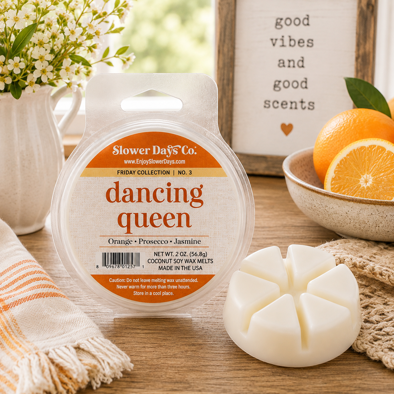 A round plastic tub of Slower D's Co. 'dancing queen' coconut soy wax melts is shown on a wooden table with the white wax melt container placed in front.
