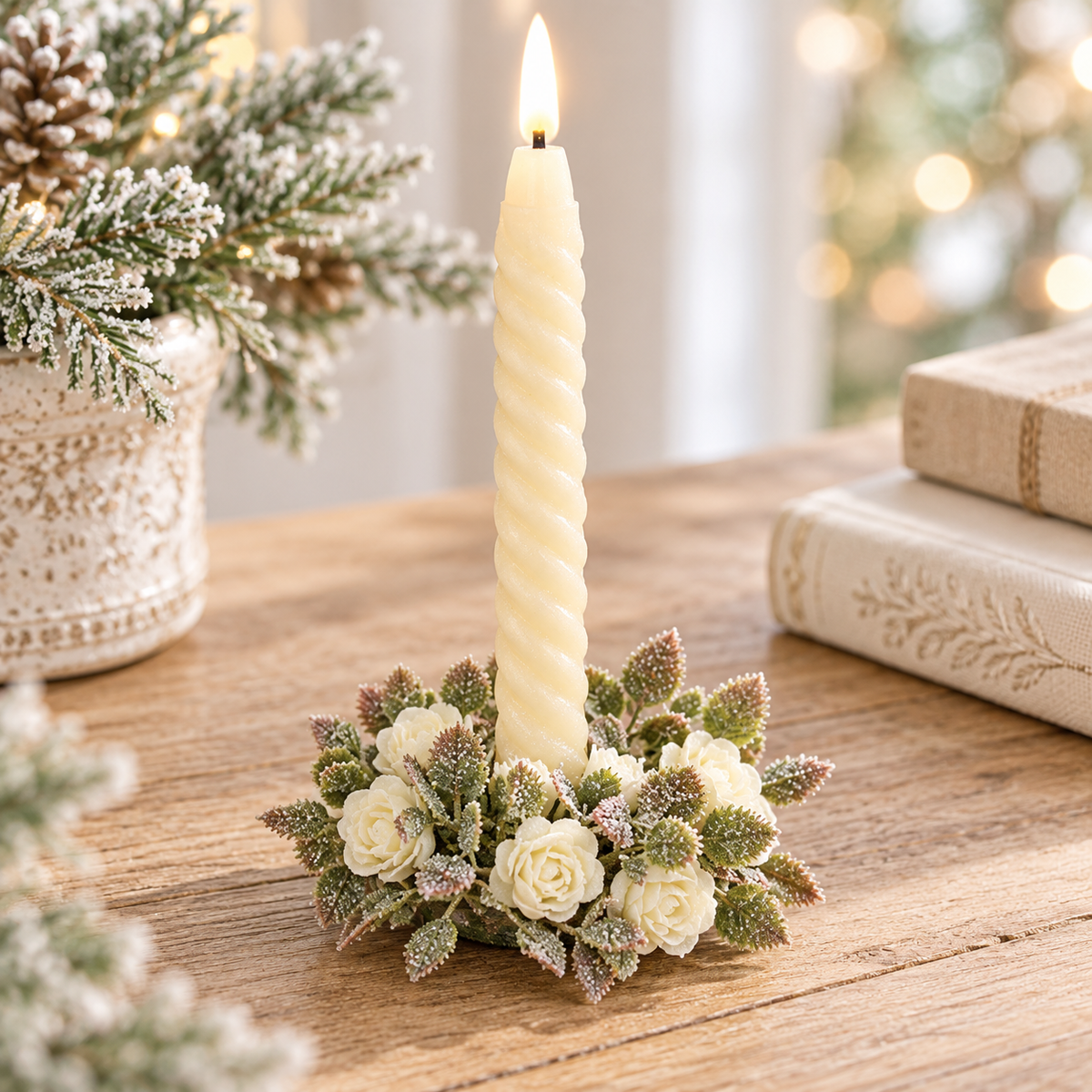 A lit cream-colored spiral candle in a small floral holder with faux white roses and frosted greenery, displayed on a wooden table in a cozy holiday setting.