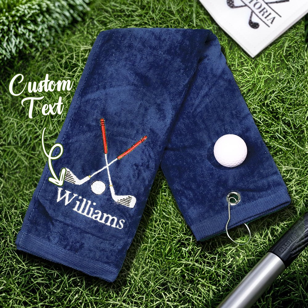 A navy blue golf towel with the customer's personalized embroidered last name, featuring a sturdy clip for easy attachment to golf bags or backpacks.