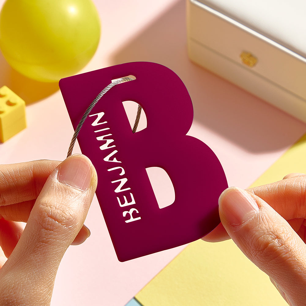 A close-up of hands gently holding the red letter B, highlighting its 3D printed design.