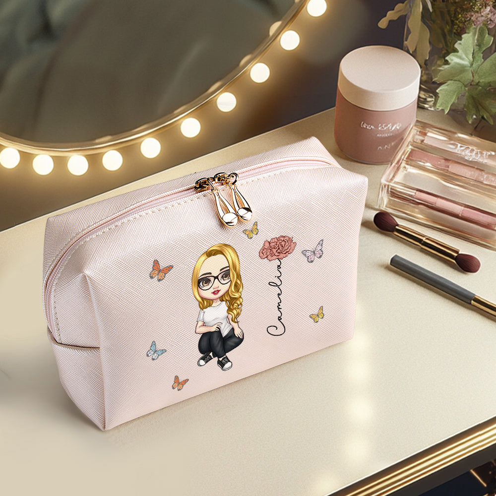 A pink personalized makeup bag sitting on a makeup table, featuring a custom character, birth flower, and name, showcasing the personalized design in a stylish setting.