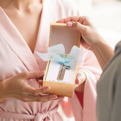 A picture of the "something blue" charm being presented as a gift, with the charm displayed in a box, gently held in hands to show it as part of the thoughtful presentation.