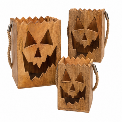 Set of three natural wood jack o lantern luminaries with cutout pumpkin faces and rope handles