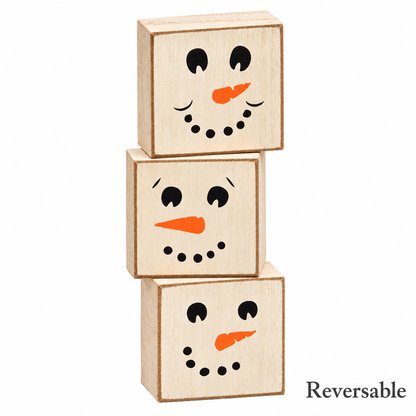 Three stacked wooden toy blocks with snowman faces, shown on a white background with the word 'Reversible' in the bottom right corner.