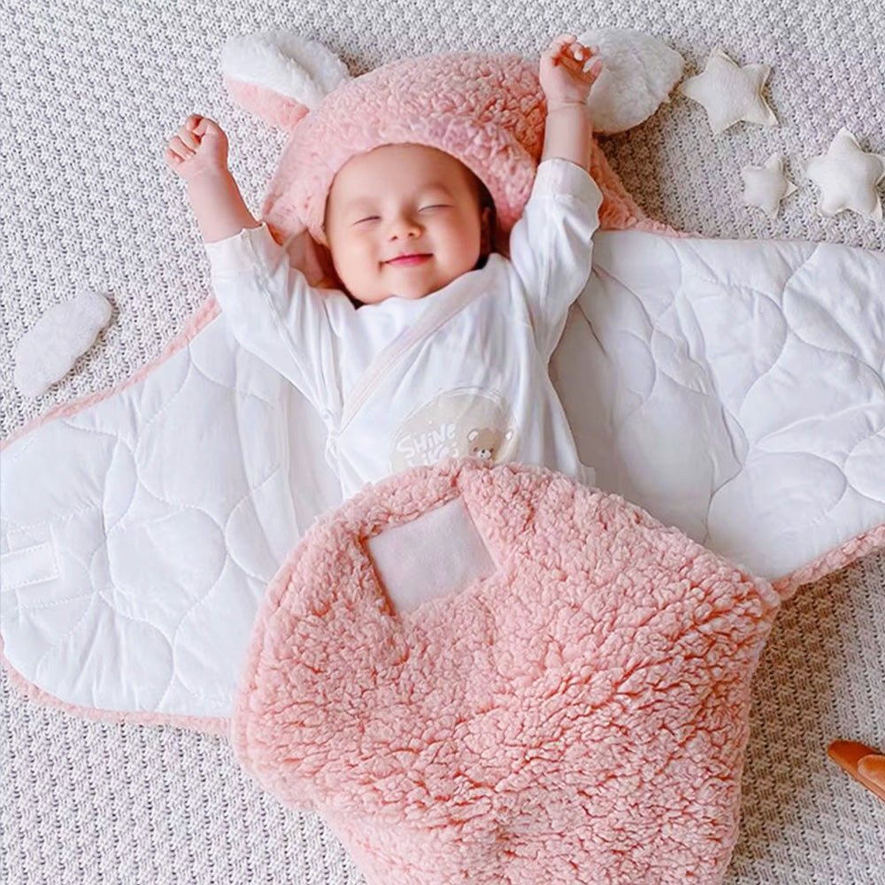 A sleeping baby in the pink bag-style swaddle, with the blanket open to reveal the velcro closure.