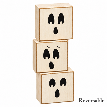 Three stacked wooden toy blocks with black ghost face designs, shown on a white background with the word 'Reversible' in the bottom right corner.