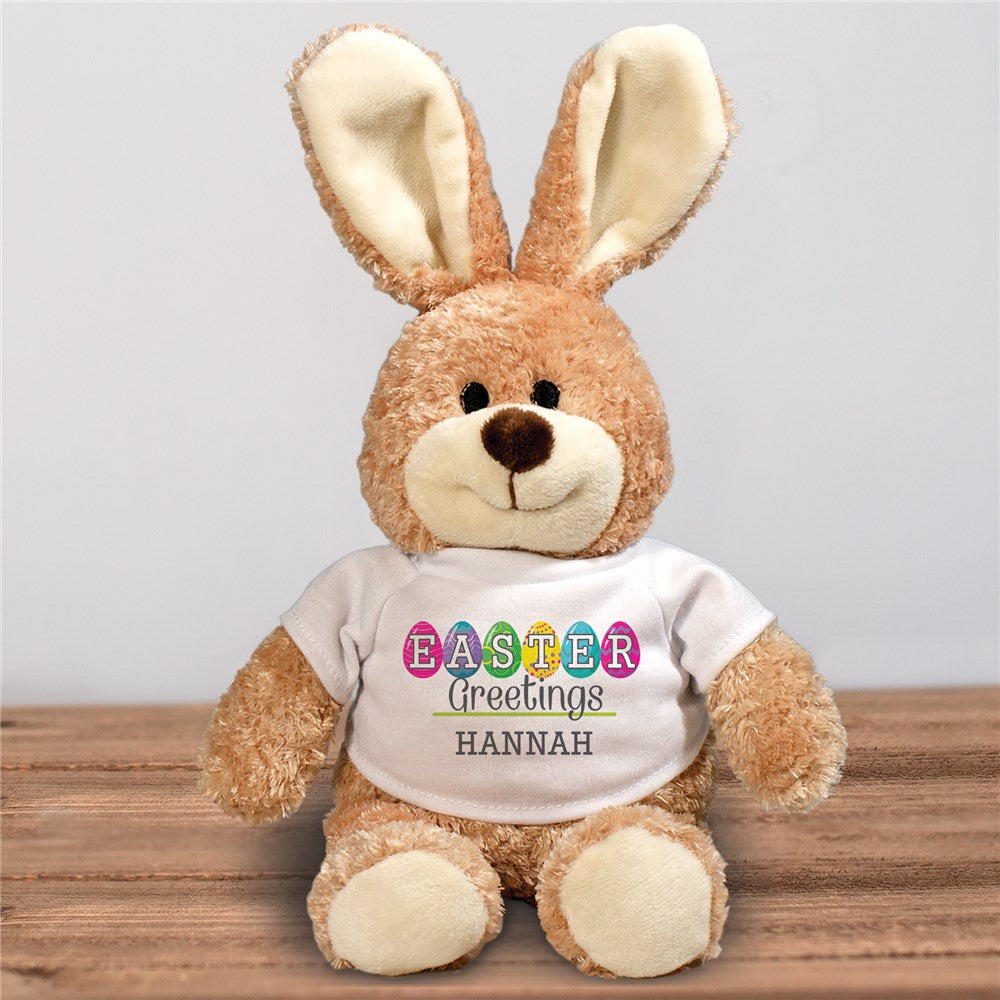 Soft plush Personalized Easter Egg Greetings Brown Bunny, featuring a custom name on an Easter egg-themed t-shirt. A cuddly, festive Easter gift for kids.