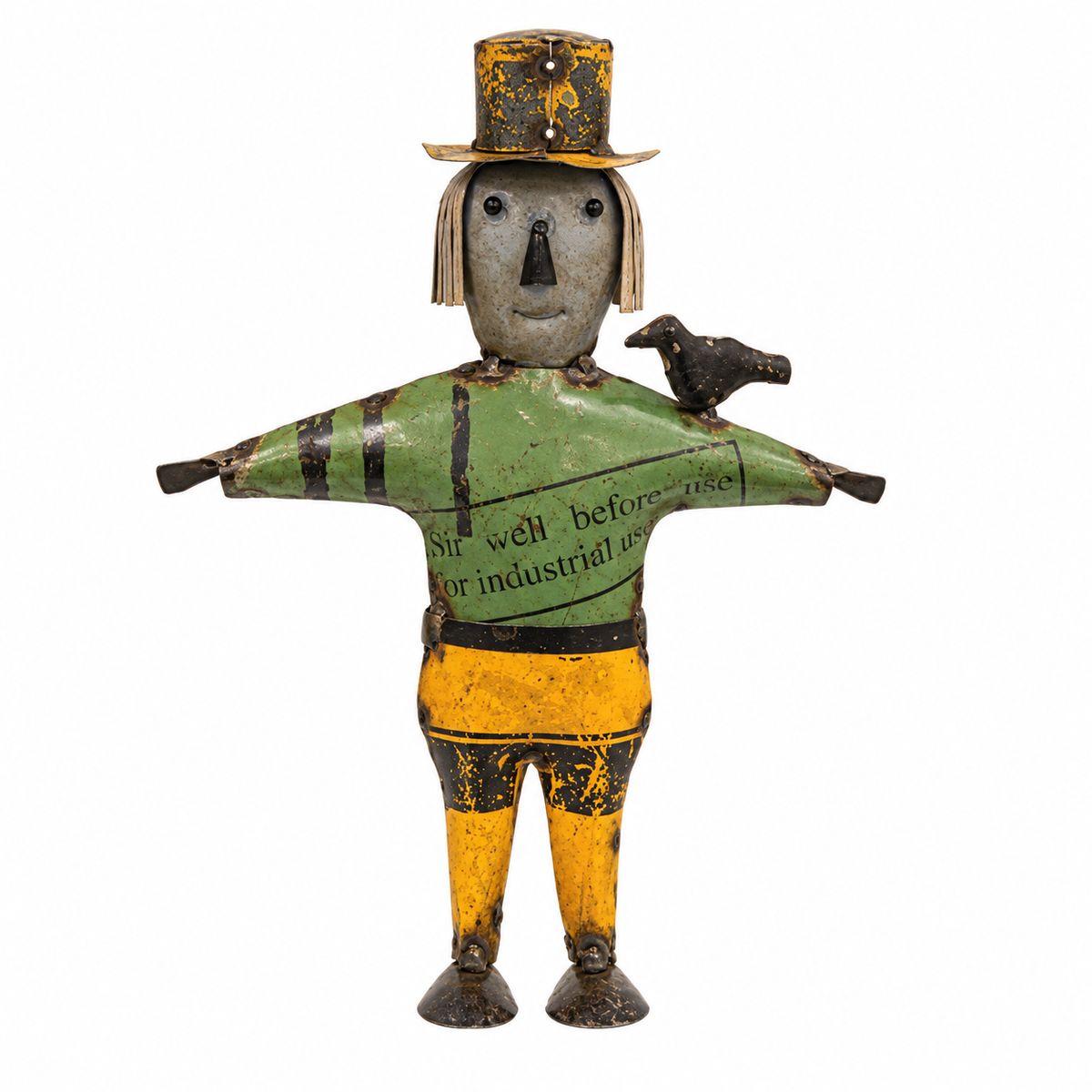 Vintage painted tin toy scarecrow with a gray face, green shirt, yellow pants, and a small black bird on its shoulder, isolated on a white background.