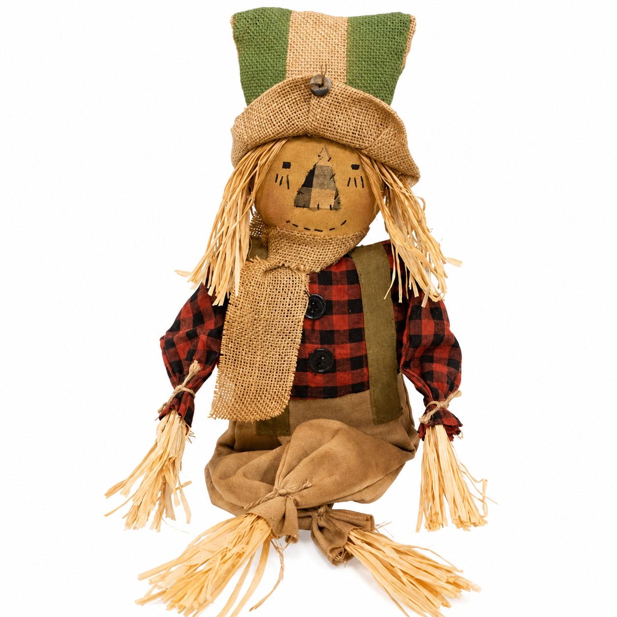 A rustic fabric scarecrow doll with a tan burlap face, straw hair, a green and tan hat, a red and black plaid shirt, a tan scarf, and tan pants, isolated on a white background.