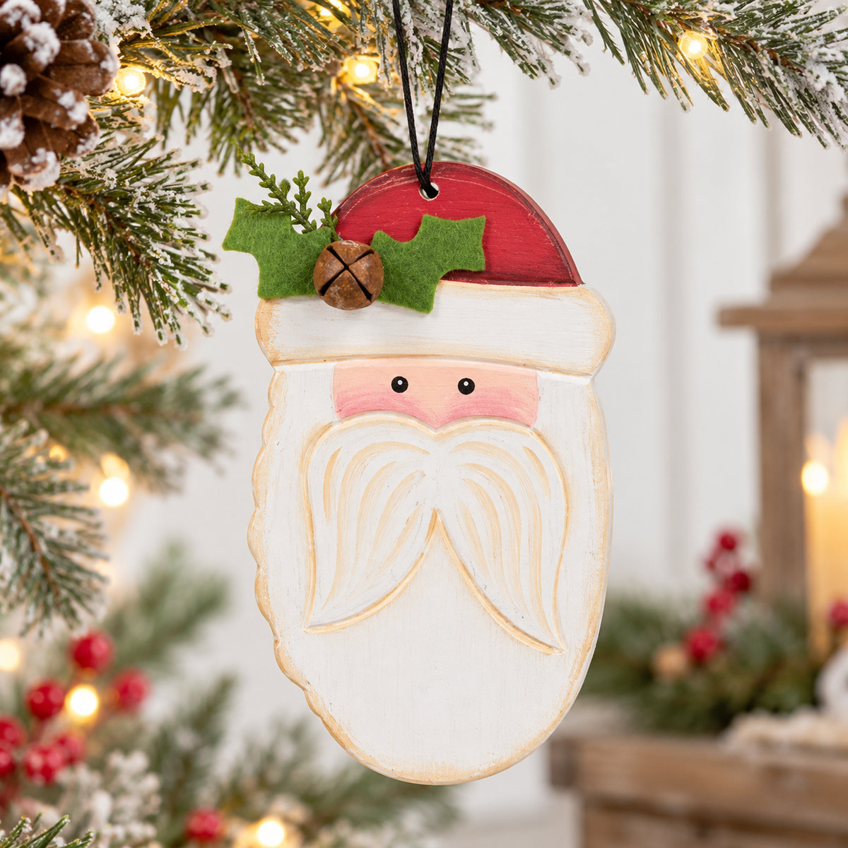A hand-painted wooden Santa Claus face ornament hanging from a decorated Christmas tree with warm string lights in the background.