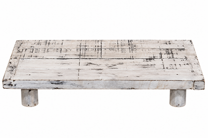 A rustic rectangular wooden platform table with a distressed white and gray finish, supported by two short cylindrical legs, shown against a plain white background.