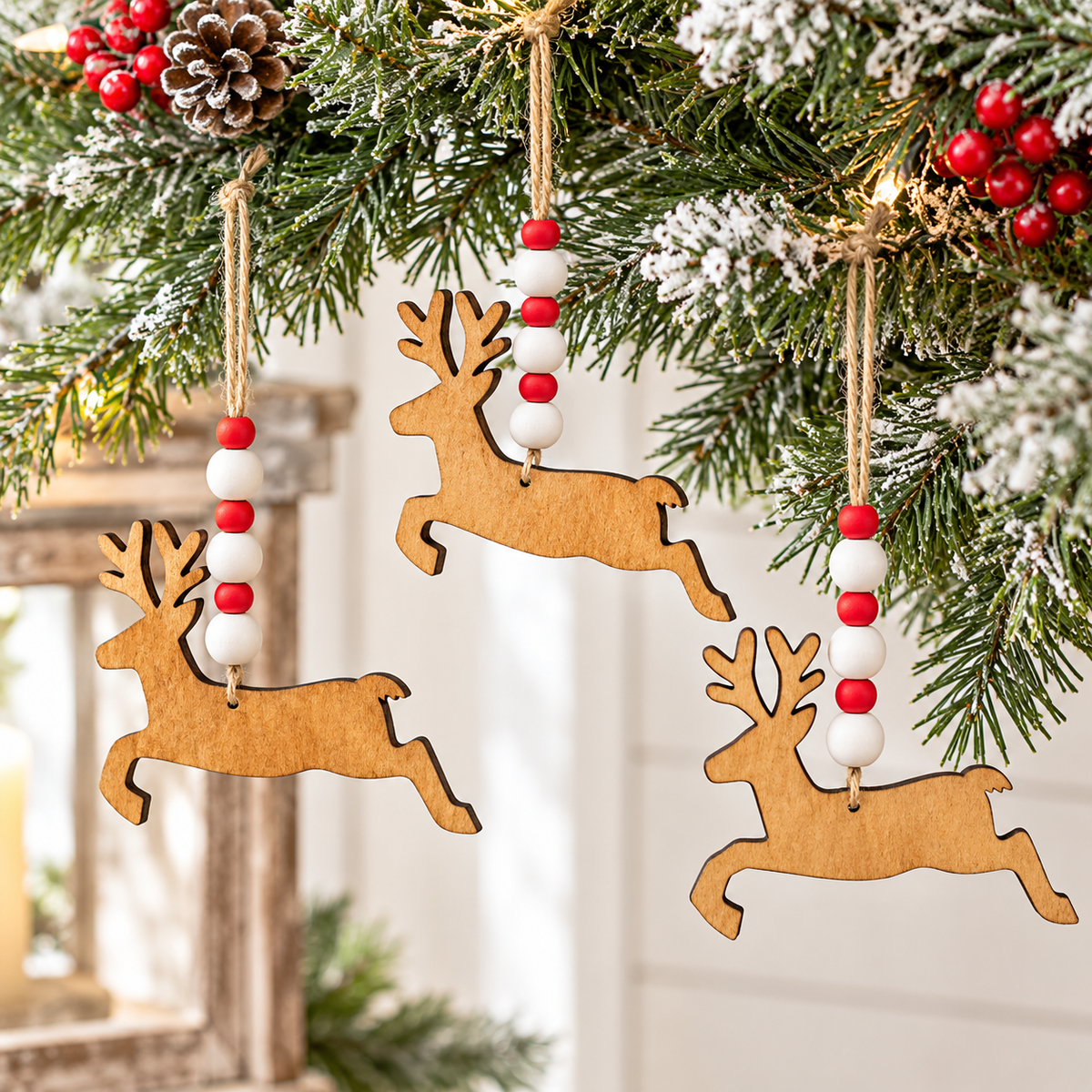 Three wooden reindeer Christmas tree ornaments with red and white bead garlands hanging from a decorated Christmas tree branch.