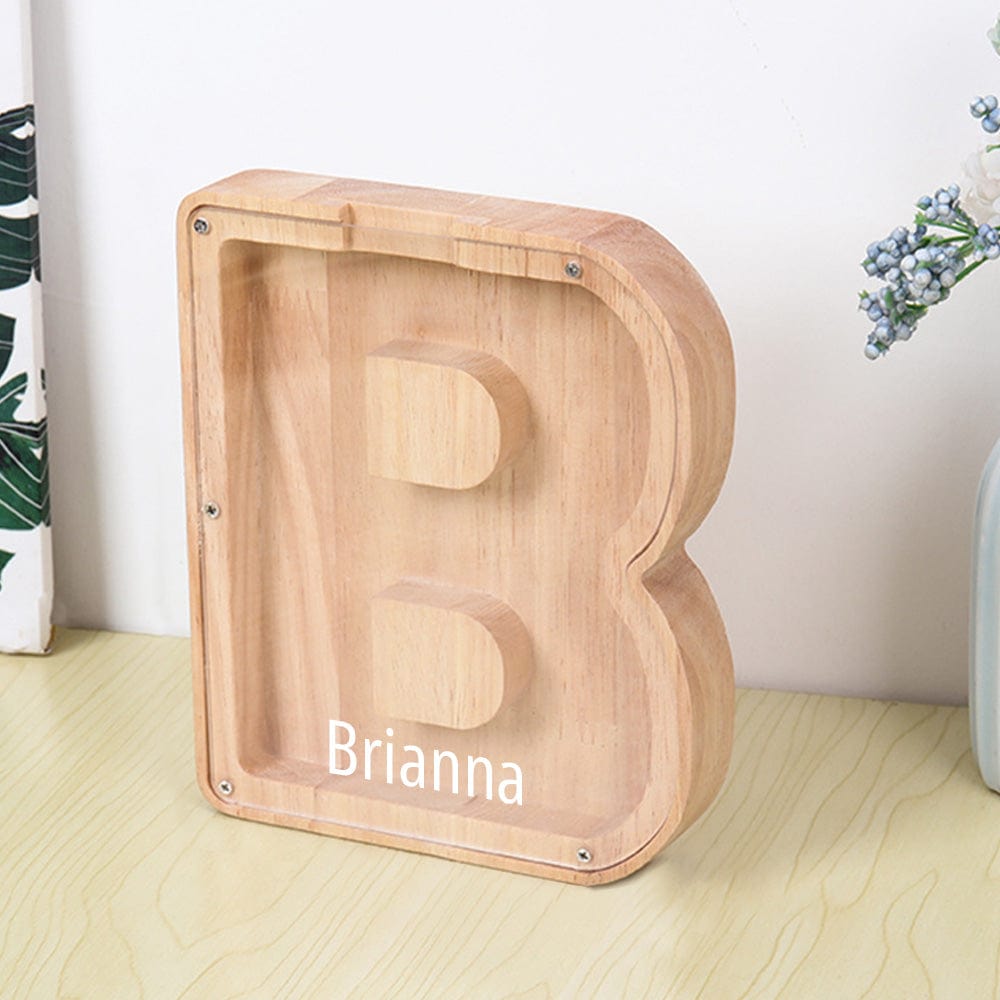 A custom letter "B" piggy bank, made of light burlywood wood with an acrylic surface, perfect for teaching children the habit of saving.