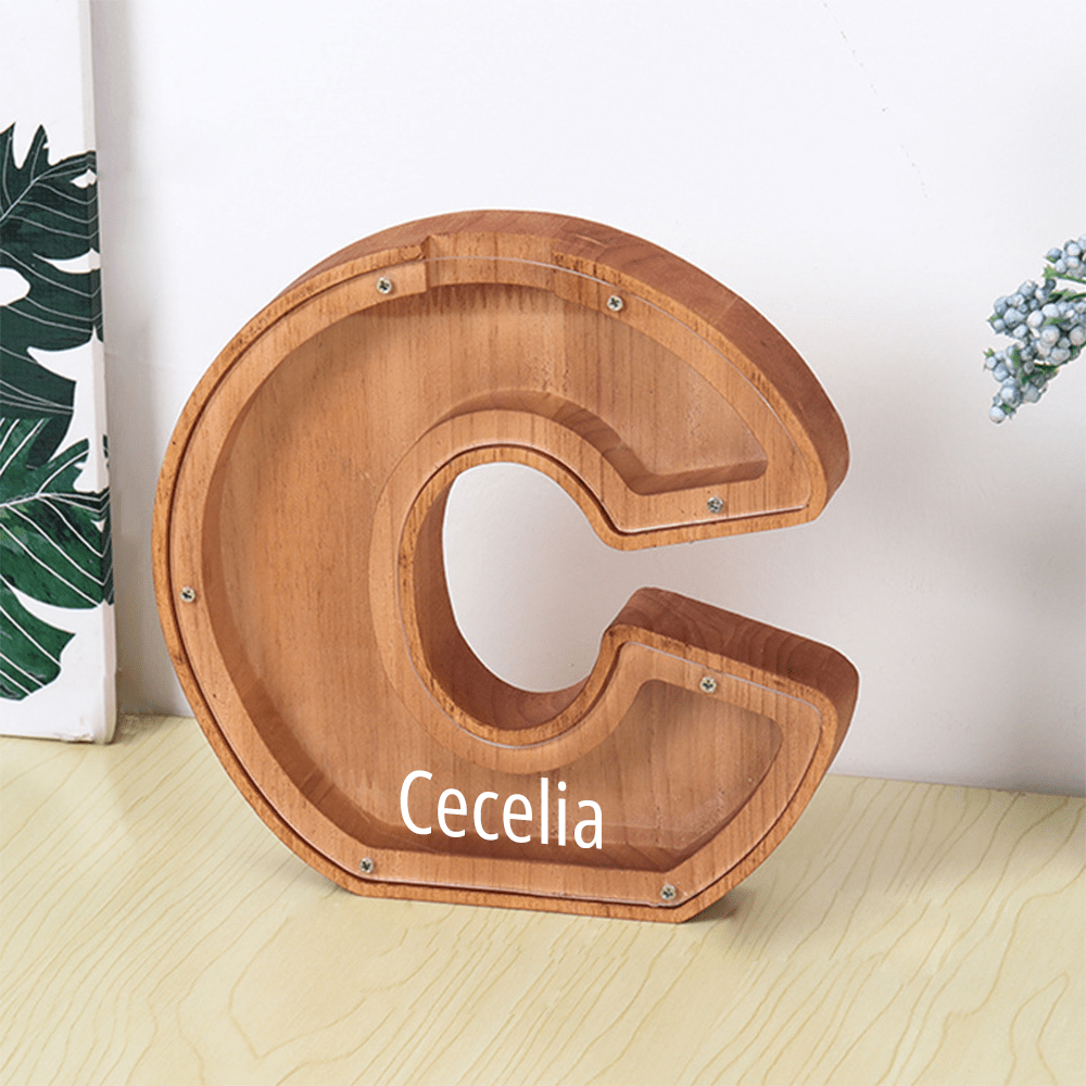 A personalized "C" wooden piggy bank, crafted from brown wood with a clear acrylic surface, perfect for young savers.