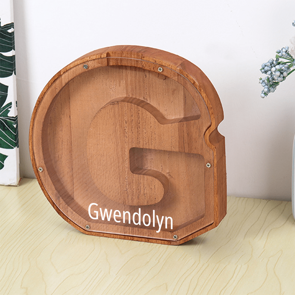 A personalized "G" piggy bank in brown with an acrylic face, allowing children to watch their savings grow over time.