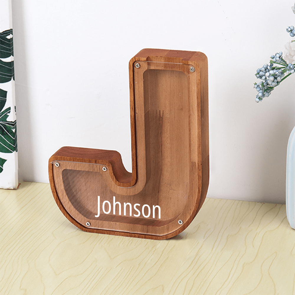 A "J" letter piggy bank in brown with a sleek acrylic surface, perfect for teaching children how to save money.