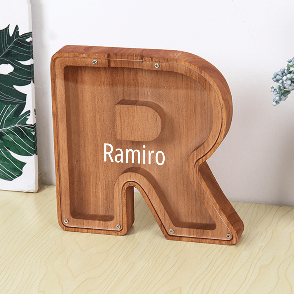 A "R" shaped piggy bank made of brown wood with a transparent acrylic front, perfect for encouraging children to save and track their funds.