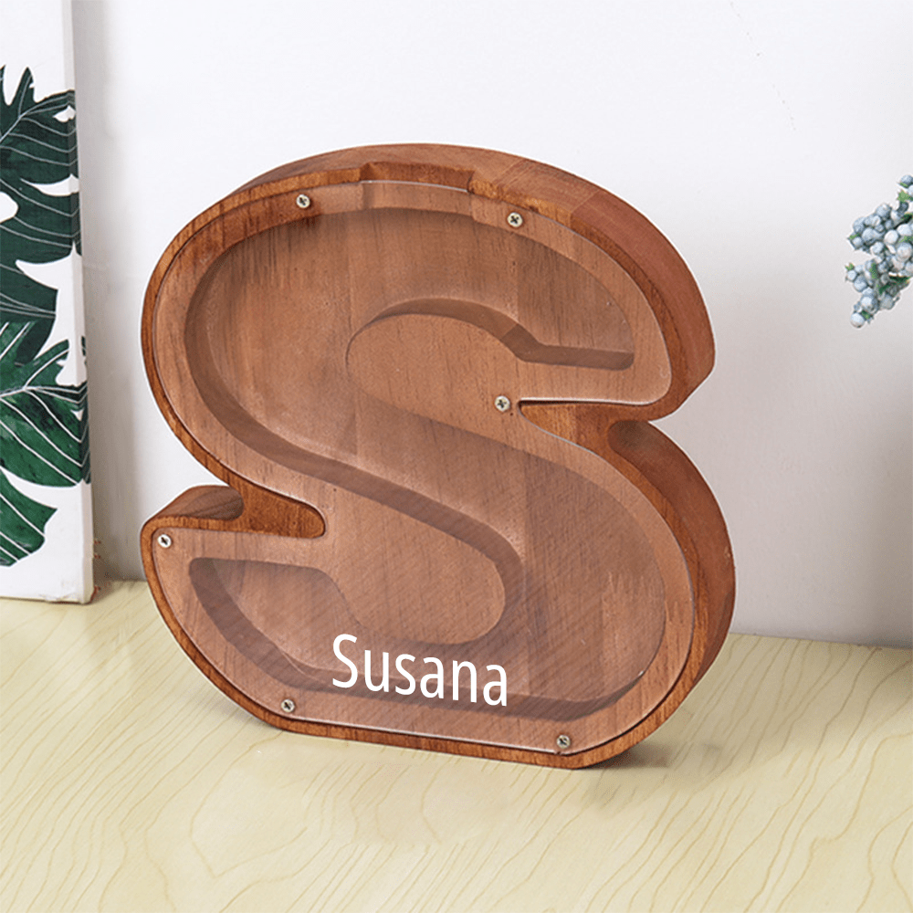 A personalized "S" piggy bank in brown, featuring a clear acrylic face for children to watch their savings grow.