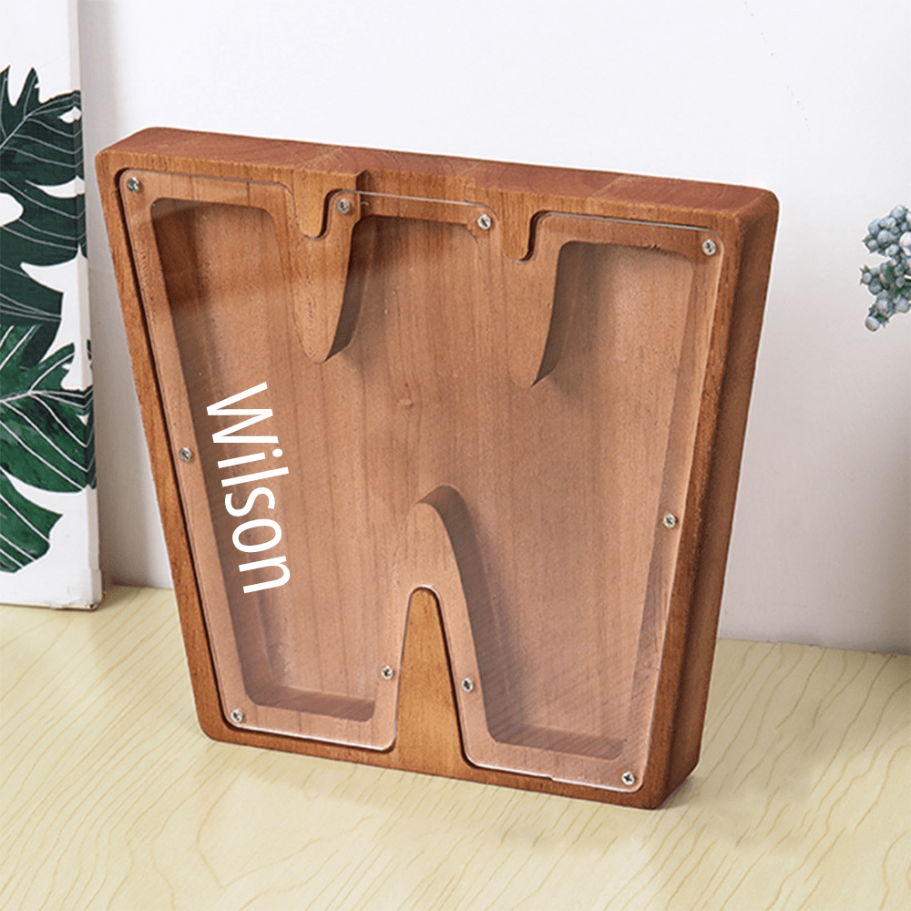 A "W" shaped piggy bank in brown, featuring an acrylic front for children to see how their savings grow over time.