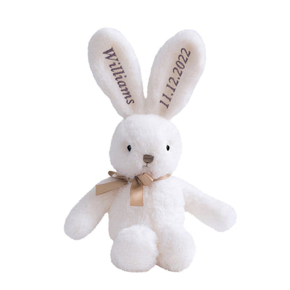 Embroidered bunny on display – A white bunny with purple embroidery sitting against a plain background.